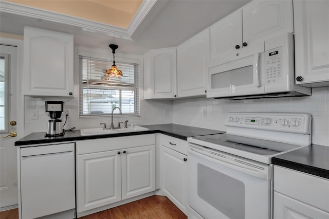 kitchen featuring white appliances, white cabinets, dark countertops, and a sink