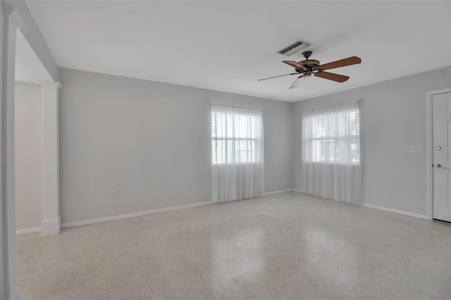 empty room with visible vents, ceiling fan, speckled floor, and baseboards