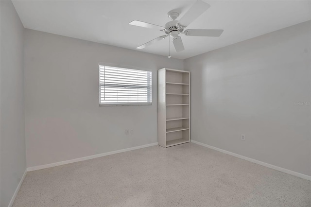 empty room with speckled floor, baseboards, and ceiling fan