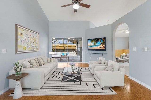 living area with baseboards, ceiling fan, arched walkways, and wood finished floors