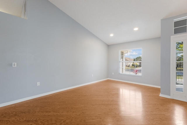 empty room with lofted ceiling, light wood finished floors, plenty of natural light, and baseboards