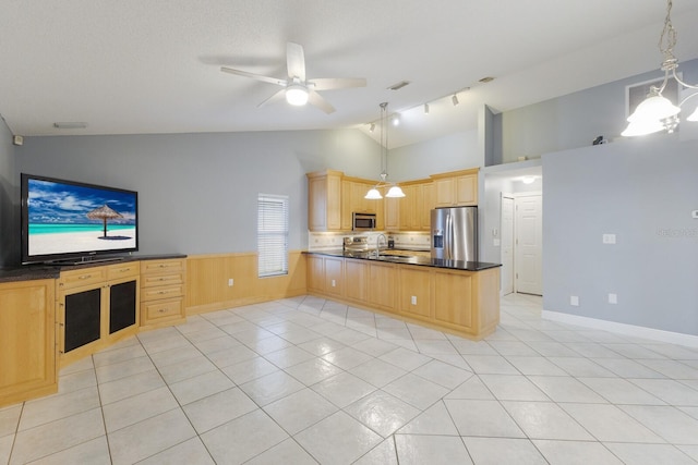 kitchen with dark countertops, lofted ceiling, appliances with stainless steel finishes, a peninsula, and light brown cabinets