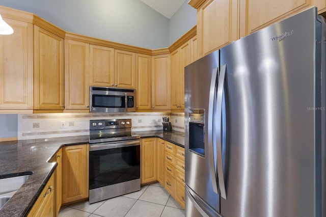 kitchen featuring light brown cabinetry, appliances with stainless steel finishes, light tile patterned flooring, and decorative backsplash