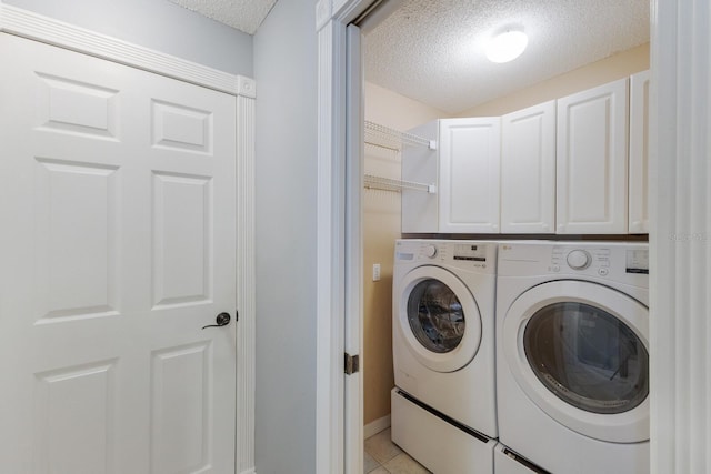 laundry room featuring cabinet space, independent washer and dryer, a textured ceiling, and light tile patterned floors