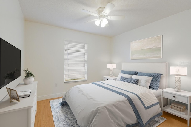 bedroom featuring light wood-type flooring, baseboards, and a ceiling fan