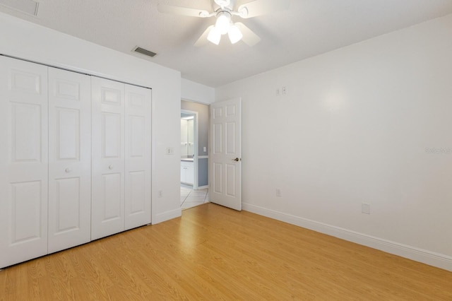 unfurnished bedroom featuring light wood-style floors, baseboards, visible vents, and a closet