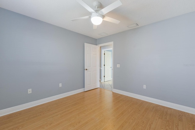 unfurnished room with a ceiling fan, light wood-type flooring, visible vents, and baseboards