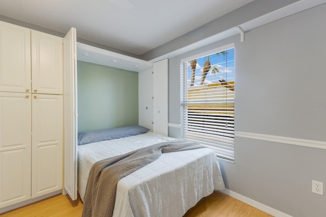 bedroom with light wood finished floors and baseboards