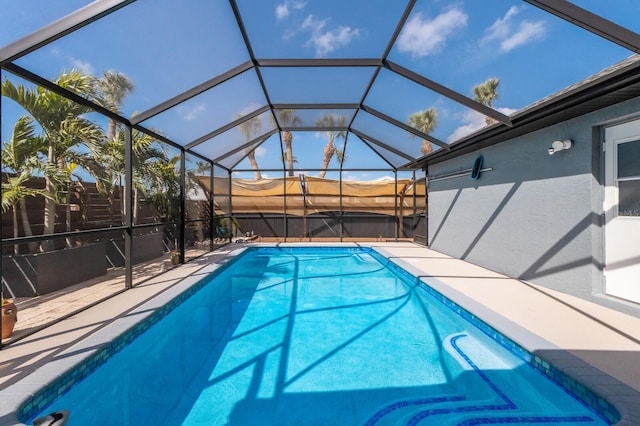 view of swimming pool with glass enclosure, a patio, and a fenced in pool