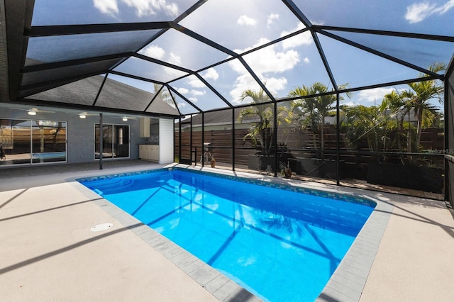 outdoor pool with a lanai, a patio area, and ceiling fan