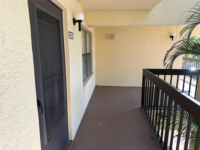 view of exterior entry with a balcony and stucco siding