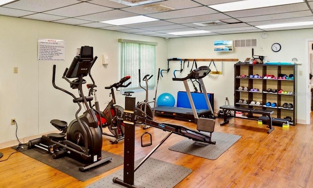 exercise area featuring a paneled ceiling, visible vents, and wood finished floors