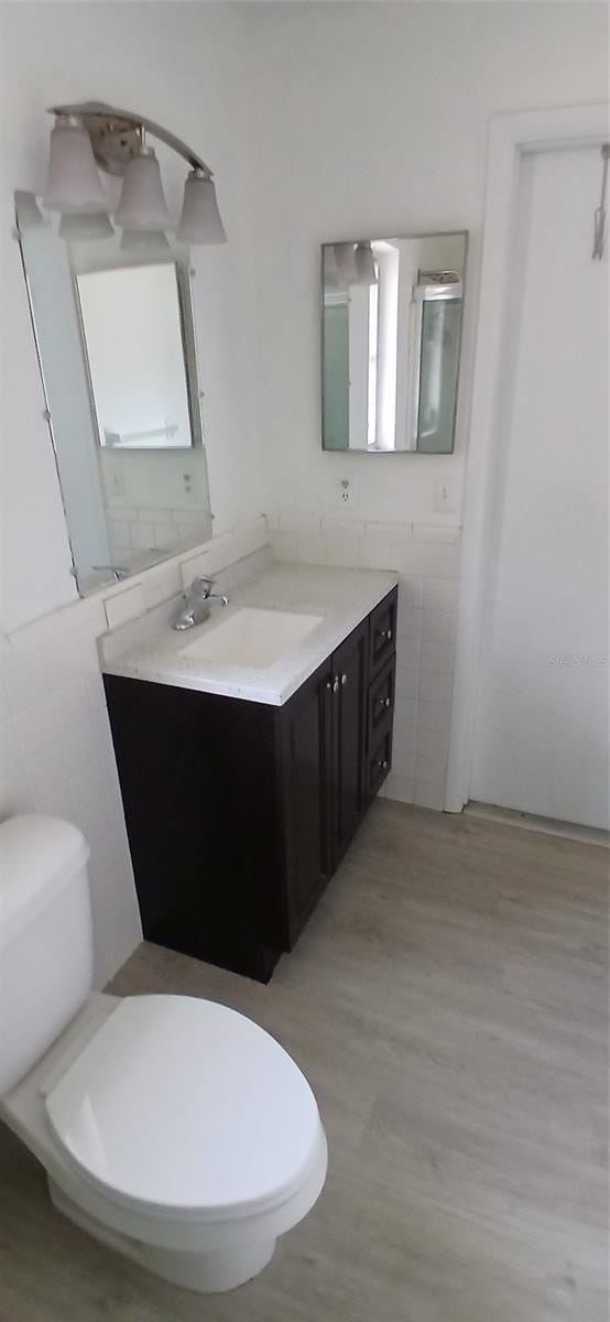 3013 Yarmouth Dr W, Bradenton, FL 34205 - bathroom featuring tile walls, vanity, and wood finished floors