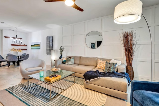 living room with light tile patterned floors, a decorative wall, and ceiling fan with notable chandelier