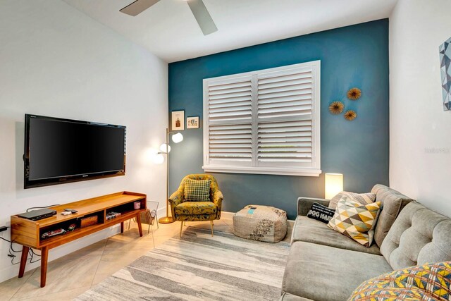 tiled living area with ceiling fan and baseboards