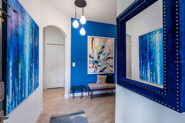 corridor featuring arched walkways, tile patterned flooring, and baseboards