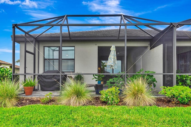 back of house featuring glass enclosure, a patio, and stucco siding