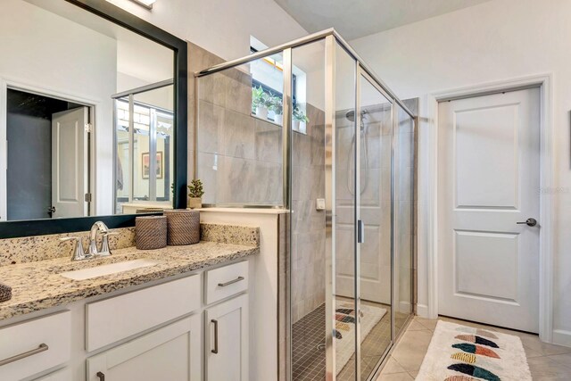 full bathroom with a stall shower, vanity, and tile patterned floors