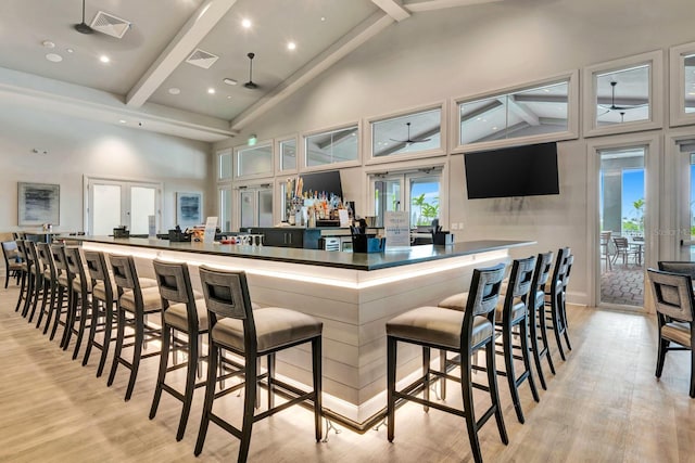 kitchen featuring light wood finished floors, french doors, beamed ceiling, and a large island