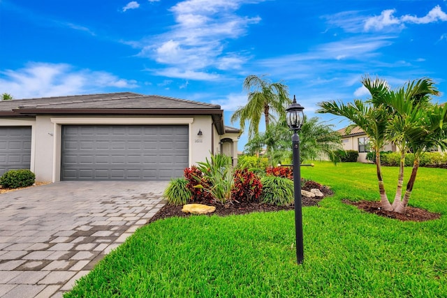 view of front of house featuring a front lawn, decorative driveway, an attached garage, and stucco siding