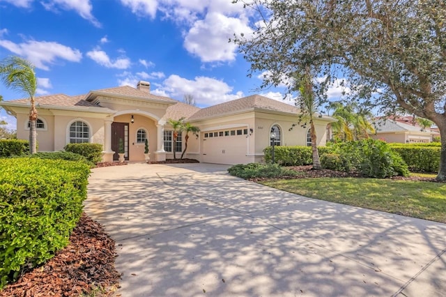 mediterranean / spanish house featuring driveway, a chimney, an attached garage, and stucco siding