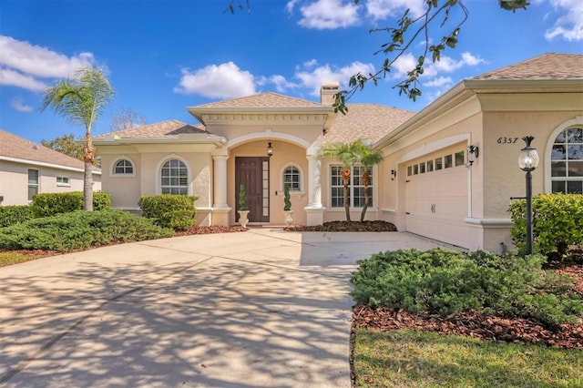 mediterranean / spanish-style house featuring a chimney, an attached garage, and stucco siding