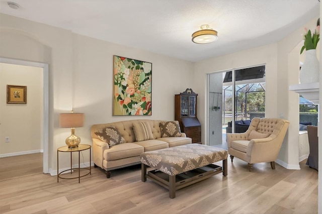 living area featuring a sunroom, baseboards, and light wood finished floors