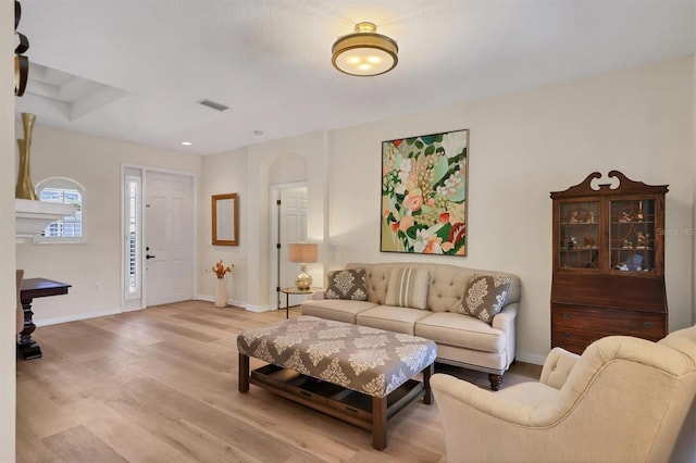 living area featuring light wood-type flooring, visible vents, and baseboards