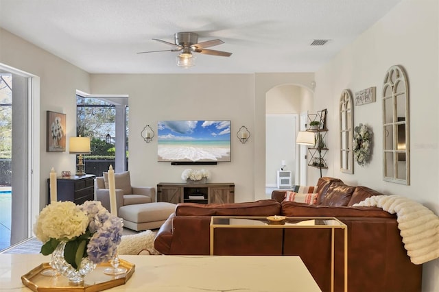 living area featuring visible vents, arched walkways, and a ceiling fan