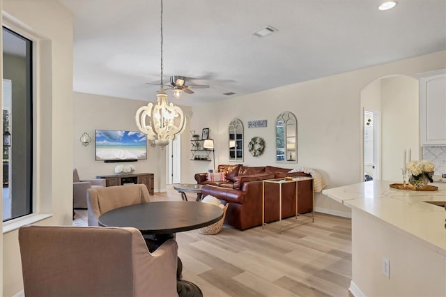 dining room with visible vents, arched walkways, baseboards, light wood-style flooring, and an inviting chandelier