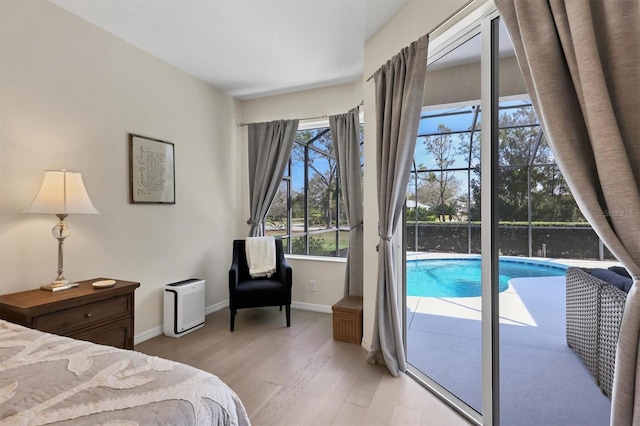 bedroom featuring access to outside, baseboards, and light wood finished floors