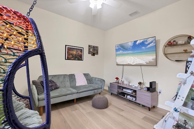 living area featuring a ceiling fan, wood finished floors, visible vents, and baseboards