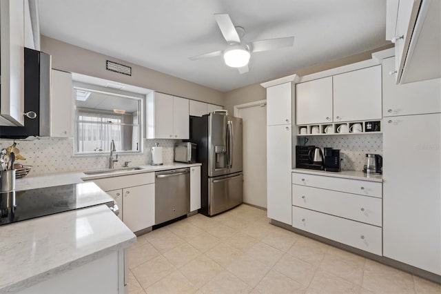 kitchen with backsplash, appliances with stainless steel finishes, white cabinets, and a sink