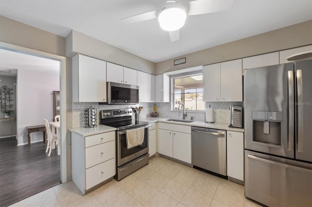 kitchen featuring appliances with stainless steel finishes, light countertops, a sink, and backsplash