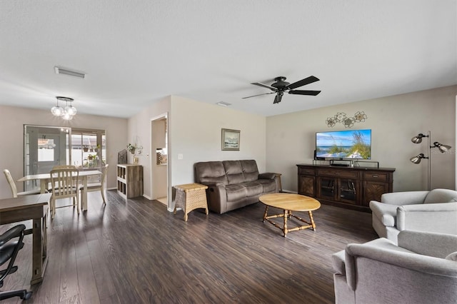 living area with ceiling fan with notable chandelier, dark wood-type flooring, and visible vents