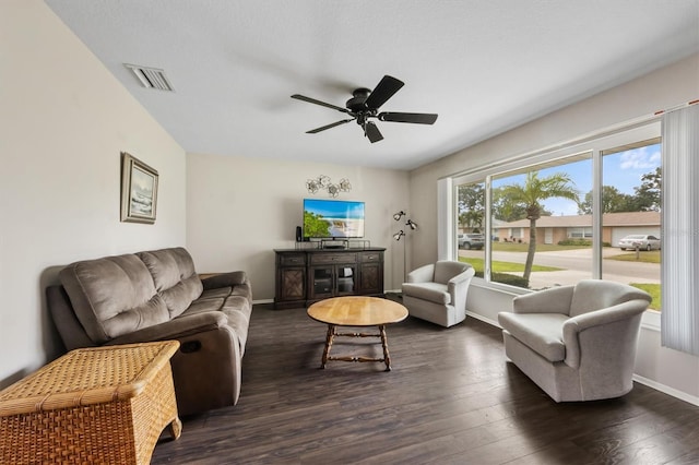 living room with a ceiling fan, visible vents, dark wood finished floors, and baseboards