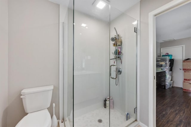 bathroom featuring a stall shower, toilet, and wood finished floors