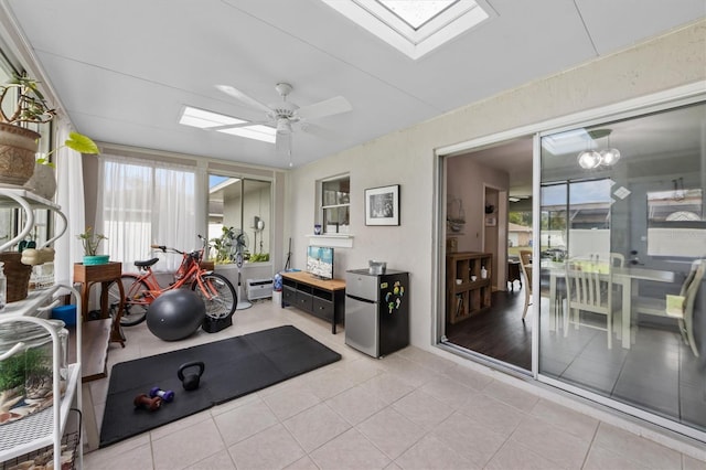 workout area featuring a skylight, tile patterned flooring, and ceiling fan