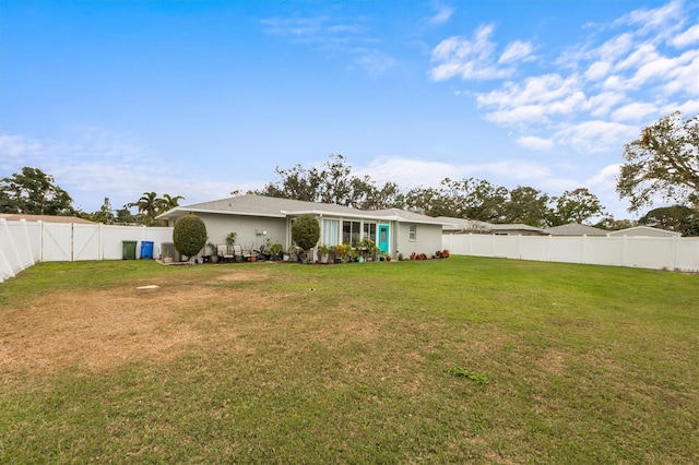 back of property with a fenced backyard and a lawn