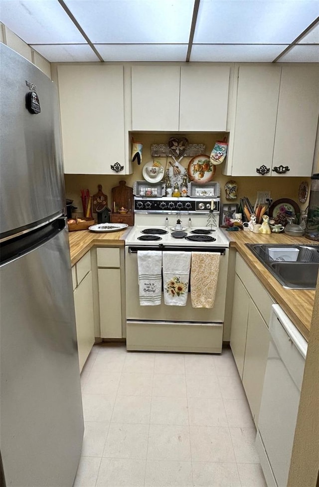 kitchen with white appliances, a drop ceiling, a sink, and wood counters