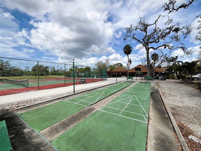 view of property's community featuring a tennis court and fence