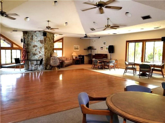 living room featuring a wealth of natural light, visible vents, lofted ceiling, and wood finished floors