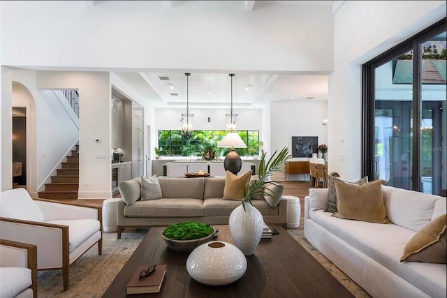 living area with an inviting chandelier, stairs, and wood finished floors