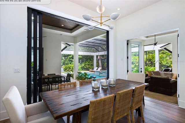 dining space with a chandelier, a sunroom, and wood finished floors