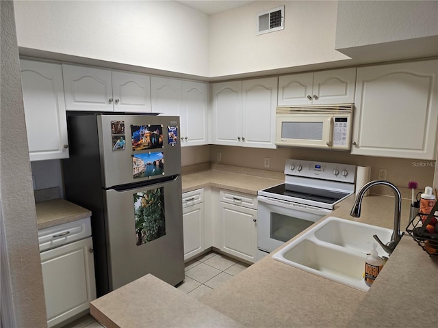 kitchen featuring visible vents, white cabinets, a sink, light tile patterned flooring, and white appliances