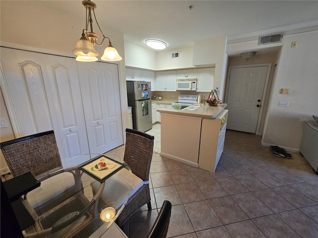 kitchen with tile patterned flooring, white appliances, visible vents, and a peninsula