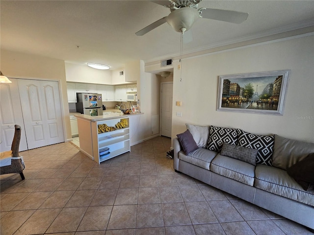 living area with ornamental molding, a ceiling fan, visible vents, and tile patterned floors