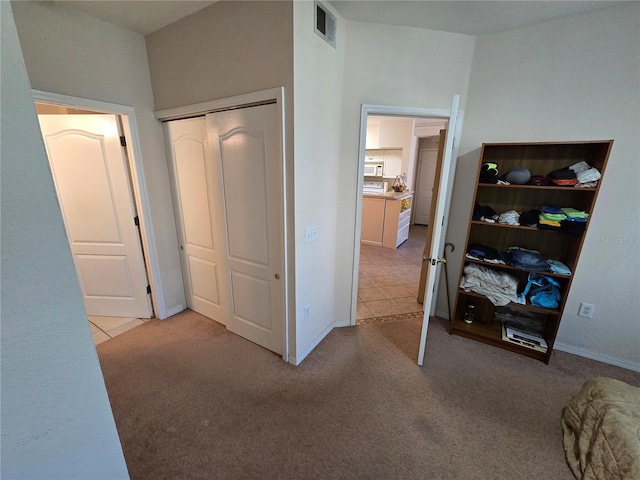 carpeted bedroom featuring visible vents, a closet, and tile patterned floors