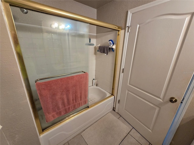 full bath with a textured wall, combined bath / shower with glass door, and tile patterned floors