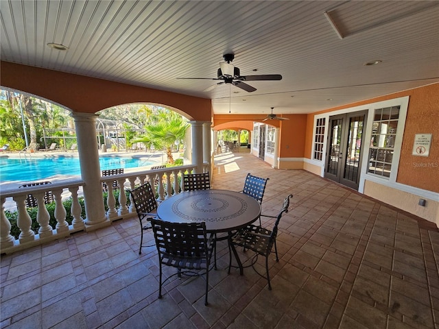 view of patio / terrace featuring french doors, outdoor dining space, a community pool, and a ceiling fan